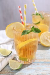 Fototapeta premium Refreshing ice tea with lemons, lime and mint on wooden table, closeup