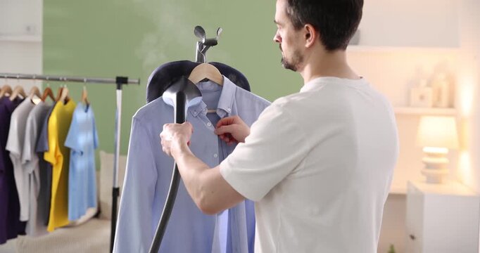 Man steaming shirt with modern steamer at home