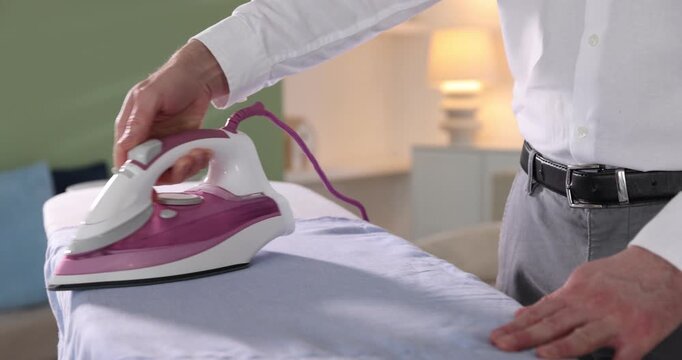 Man ironing shirt on board at home, closeup. Camera moving backwards