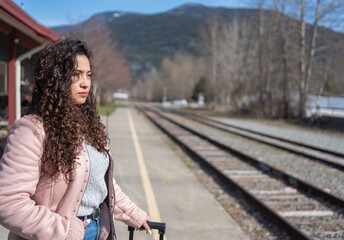 Naklejka premium A young woman is waiting for a train at the station.