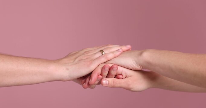 Lesbian wedding. Woman and her wife holding hands on pink background, closeup