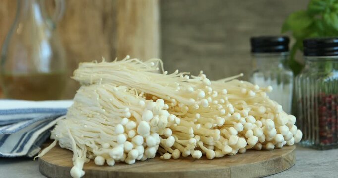 Woman putting raw enoki mushrooms on table, closeup