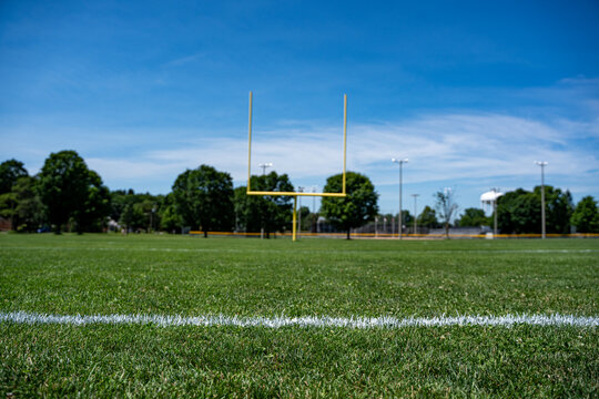 Empty American football field with yellow goalposts.