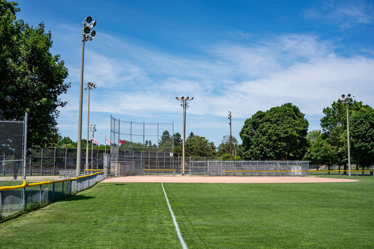 Empty outdoor baseball field with bleachers and lights.