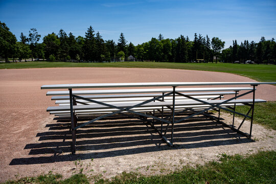 Empty metal bleachers beside community baseball field.