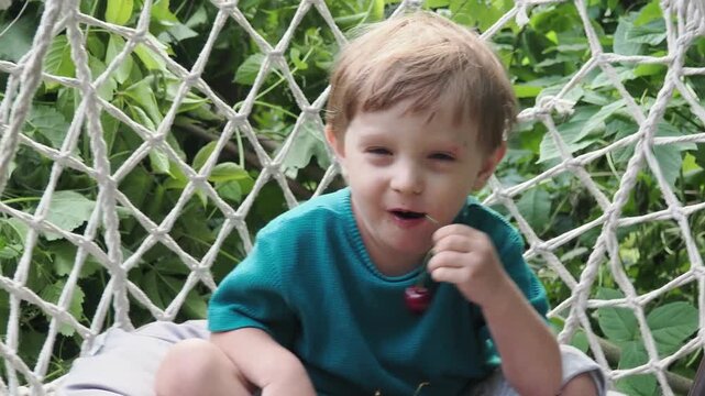 Cherry in kids mouth. Cherry fot kids. Happy kid eating ripe, sweet, juicy, fresh cherries. Child holding cherries. Concept of healthy summer food.