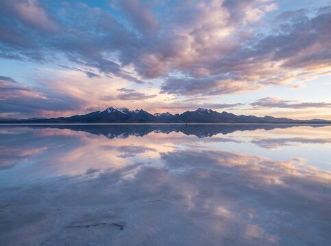 Vast Salt Flats Reflecting Dramatic Sunset Sky and Mountain Range.