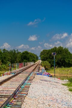 Graffiti covered railroad tracks and trestle bridge under blue sky