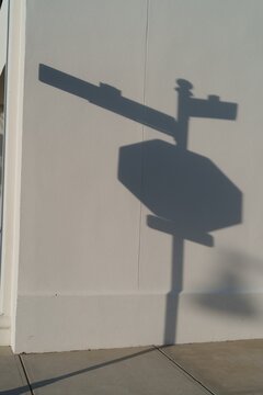 Shadow of stop sign and street sign on wall