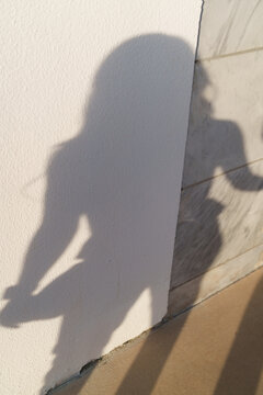 Shadow of a person taking a photo on a textured wall corner
