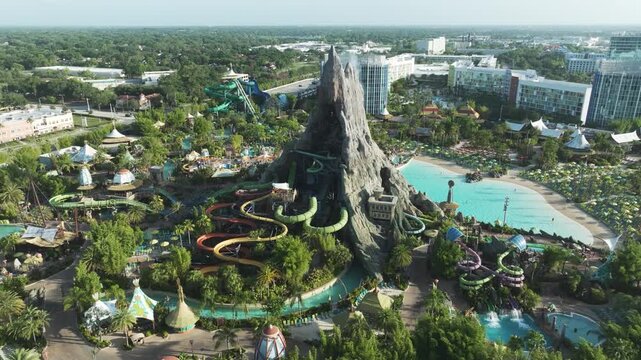 Sunny drone footage capturing the colorful curves of Volcano Bay's water slides at Universal Orlando, with tropical foliage, cabanas, and the Krakatau volcano behind.