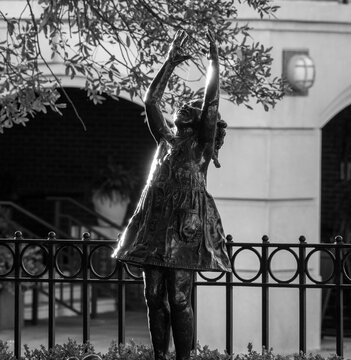 Bronze statue of girl reaching upward in dress at fountain