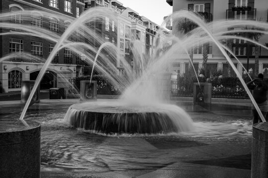 Water fountain jets arching in an urban plaza with buildings