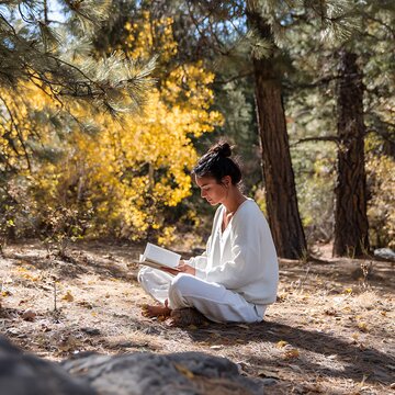 Young Woman Reading Book in Sunlit Autumn Forest