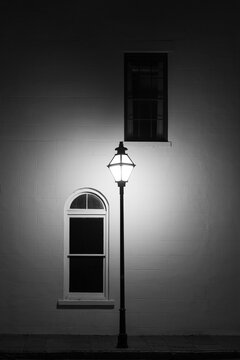Illuminated lamp post against building wall at night