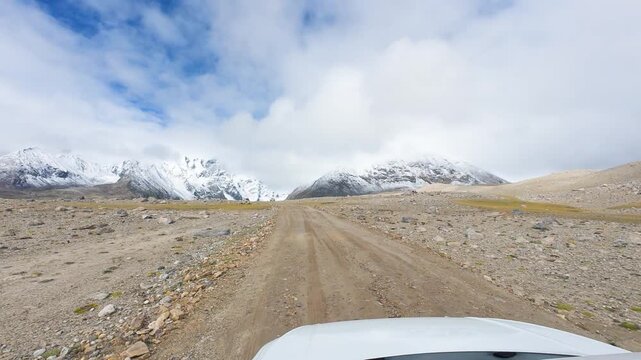 Driving on the offroad way to Ama Drime Snow Mountain in Shigatse, Tibet, China, the rutted mud road full of deep muddy craters and horribly bumpy. POV from car, 4k real time footage travel concept.