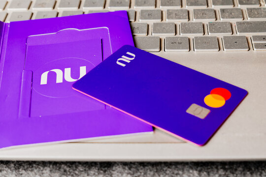 Purple Nubank Mastercard credit card with packaging kit on laptop keyboard closeup
