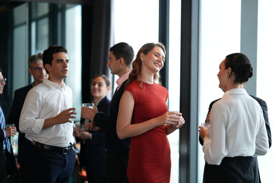 A lively business networking crowd, mingling and laughing at the reception at a bright hotel reception by the windows, for a polished travel tourism and lifestyle theme.