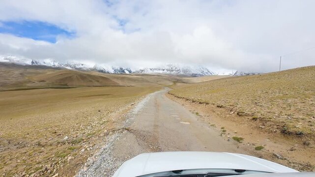 Driving on the offroad way to Ama Drime Snow Mountain in Shigatse, Tibet, China, the rutted mud road full of deep muddy craters and horribly bumpy. POV from car, 4k real time footage travel concept.