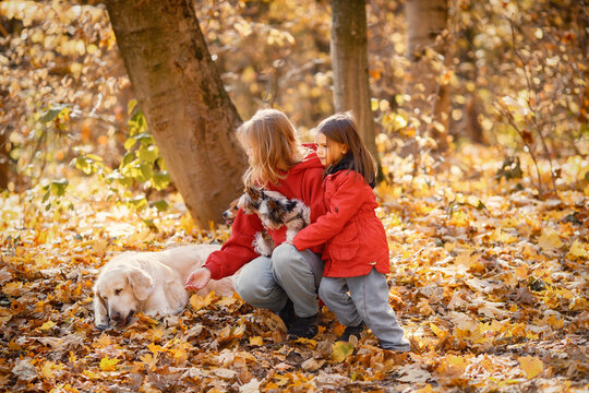 Mother and daughter playing in autumn forest with dogs