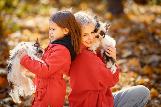 Mother and daughter sitting on a blanket in autumn forest with dogs