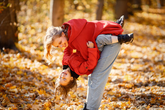 Mother and daughter walking and playing in autumn forest