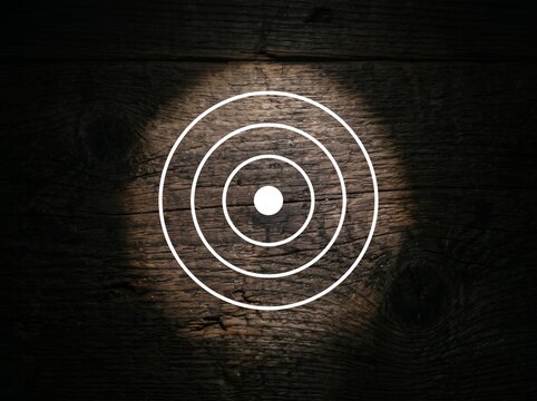 Target symbol with spotlight on dark wood background.