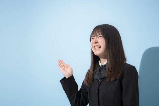 水色背景で制服で立つ笑顔の女子中学生や高校生のイメージ　オススメや紹介はコチラのポーズ