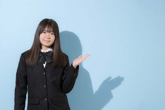 水色背景で制服で立つカメラ目線笑顔の女子中学生や高校生のイメージ　オススメや紹介はコチラのポーズ