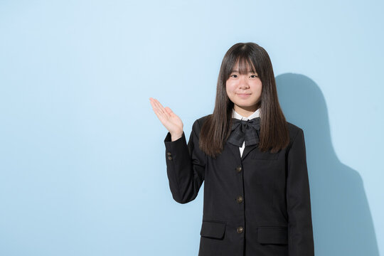 水色背景で制服で立つカメラ目線笑顔の女子中学生や高校生のイメージ　オススメや紹介はコチラのポーズ