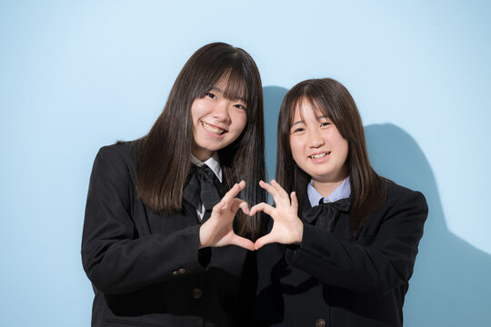 二人で手を合わせてハートを作る笑顔の日本人女子高校生　友情と青春のイメージカメラ目線笑顔