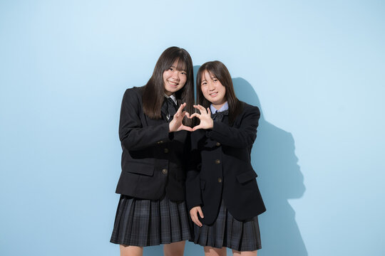 二人で手を合わせてハートを作る笑顔の日本人女子高校生　友情と青春、仲間や感謝などのイメージカメラ目線笑顔