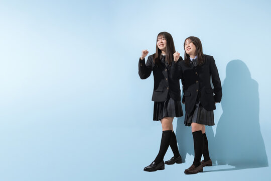 水色背景で未来や将来へ向かって走る、歩く日本人女子高生や中学生の全身　2人で前向きに進む受験や青春、合格やオープンキャンパスイメージ