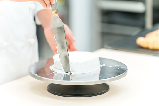 The hands of a pastry chef, cake maker, or confectioner making cakes and Western-style sweets in the kitchen.