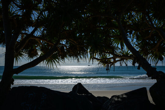 Scenic Beach View of  sunshine on water Framed by Tropical Trees and Rocks - horizontal