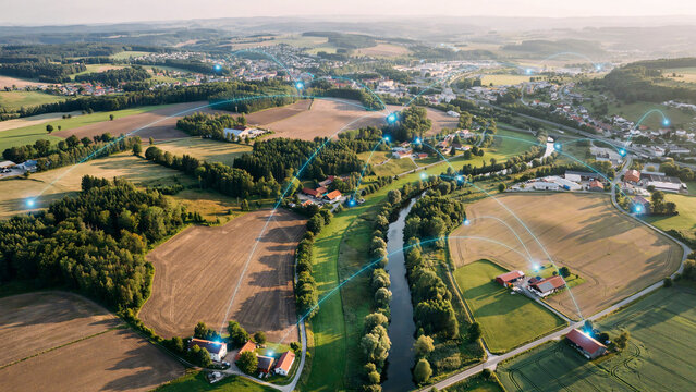 Aerial view of a rural landscape with digital network connections overlaying villages and farms representing global connectivity and infrastructure