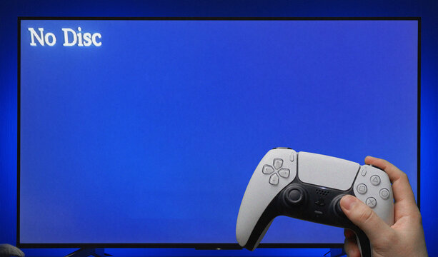 PlayStation No Disc Error Message Displayed on Blue TV Screen with PS5 Controller Held in Hand