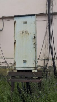 Abandoned weathered electrical utility box with rusted metal frame, tangled powe