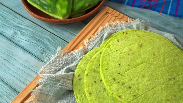 Aerial view of a stack of fresh green nopal cactus tortillas on a wooden board