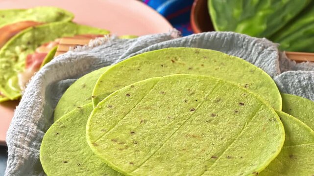 Cactus tortillas slowly rotating on a wooden base, in the background quesadillas with nopal tortilla and cactus on a clay plate
