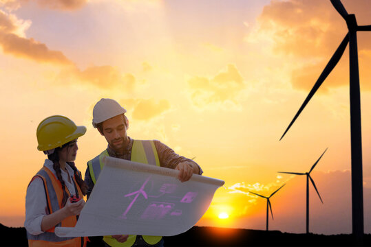 Renewable energy team planning with futuristic hologram on paper at wind turbine field, photo manipulation, not AI.