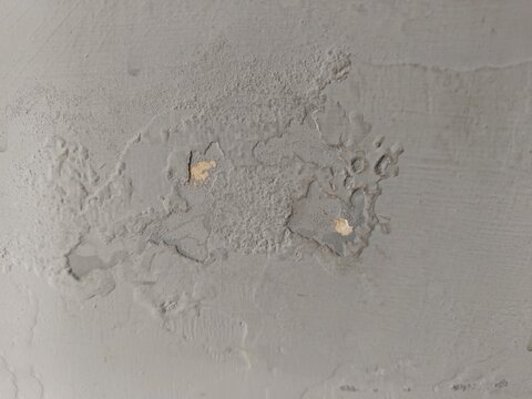 Close up of peeling and flaking grey paint on a wall caused by dampness and water damage
