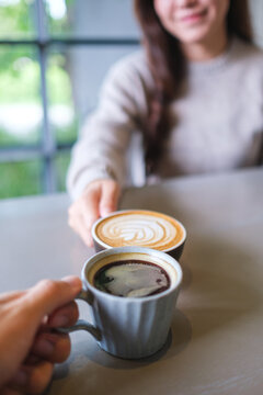 Vertical closeup image of couple people clinking coffee cups in cafe
