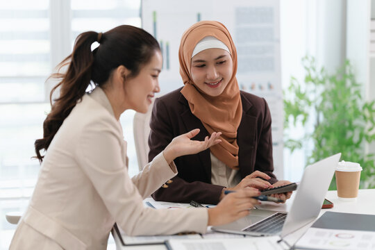 Two business colleagues multiethnic working in office, asian muslim