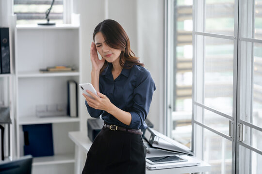 Asian woman reading some bad news on smartphone, worry and stressed