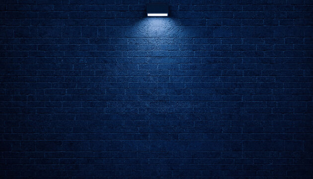 Modern outdoor wall light illuminating a dark blue brick wall