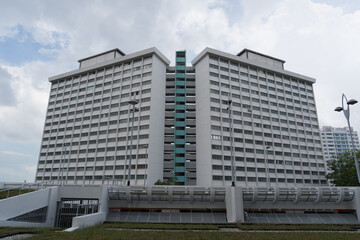 Fototapeta premium Modern high-rise apartment buildings under partly cloudy sky. Structural design features clean, repeating window patterns. Facade presents uniform, light-colored concrete exterior
