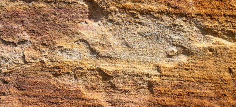 Natural yellow orange sandstone wall texture with rough layered weathered rock surface