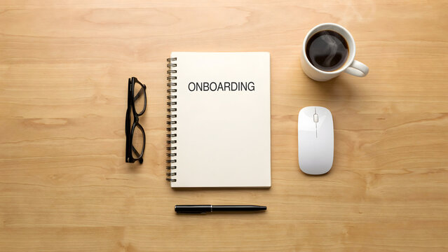 Onboarding notebook with coffee cup and office supplies on a wooden desk