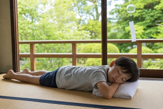 Child taking a summer nap beside a wind chime on tatami